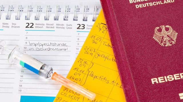  Impfpass und Reisepass auf Kalender mit Termin für Impfung