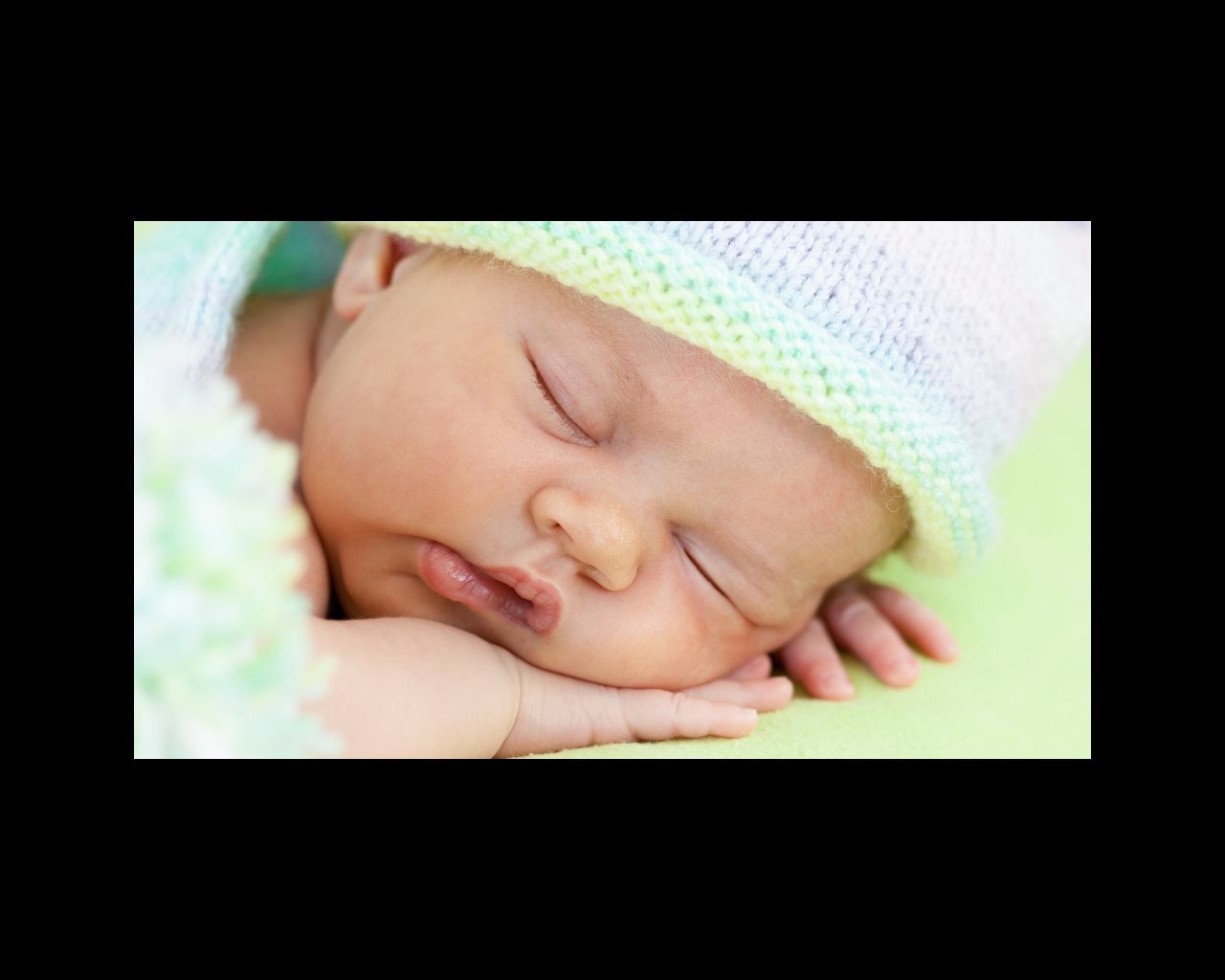 adorable baby weared cap sleeping on green