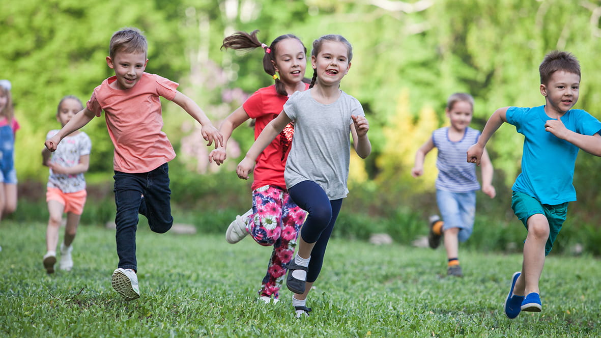 Eine Gruppe Kinder rennt über eine Wiese.