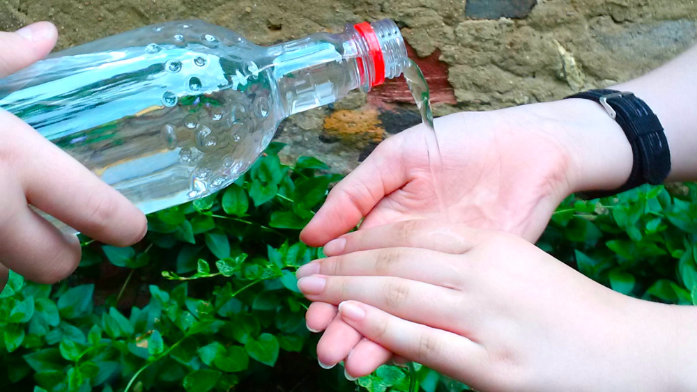 Trinkwasserqualität in Frankfurt: Jemand gießt Wasser aus einer Plastikflasche auf die Hände einer weiteren Person.