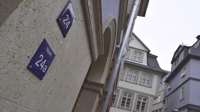 Das Bild zeigt eine Nahaufnahme von zwei dunkelblauen, quadratischen Schildern. Auf ihnen stehen in weißer Schrift die Hausnummern 24 und 24a. Sie sind an einem der neuen Gebäude in der 2018 fertiggestellten Altstadt angebracht. 