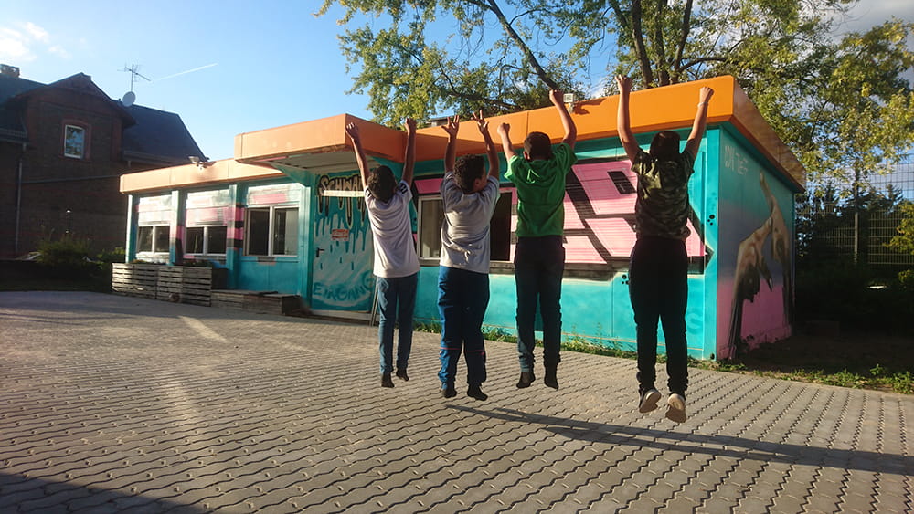 Jugendliche springen vor dem TREFF Schwanheim in die Luft
