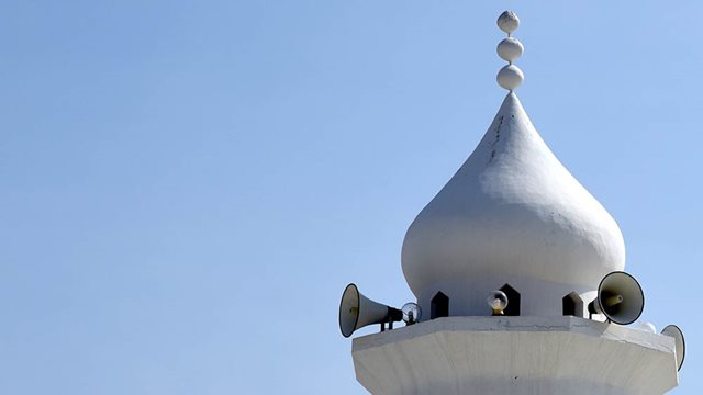 Minarett mit Lautsprechern vor strahlend blauem Himmel