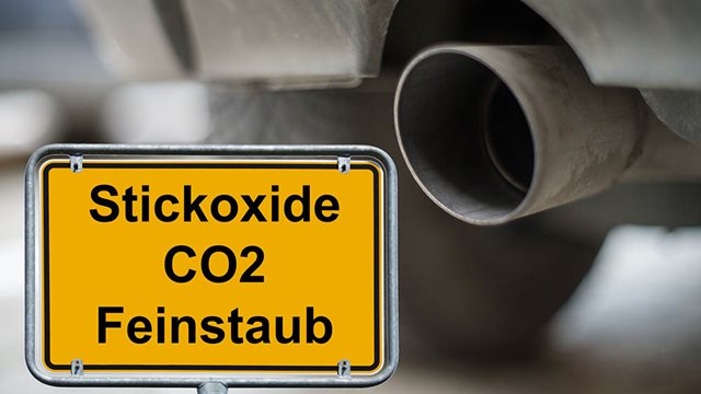 Ortsschild Stickoxide CO2 Feinstaub vor Auspuff