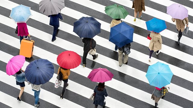 Menschen mit Regenschirmen von oben betrachtet