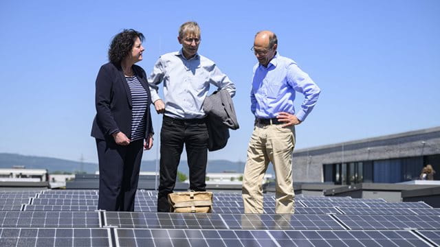 Sylvia Weber, Mathias Linder und Schulleiter Helmut Kühnberger auf dem Dach des Gymnasiums Riedberg Eine Frau und zwei Männer stehen auf dem Dach des Gymnasiums Riedberg zwischen Photovoltaik, Foto: Salome Roessler