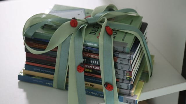 Die Schulbücherei der Georg-August-Zinn-Schule verfügt über acht Bücher in Leichter Sprache Übereinander gestapelte Bücher, die mit einer Schleife eingebunden sind, Foto: Maik Reuß