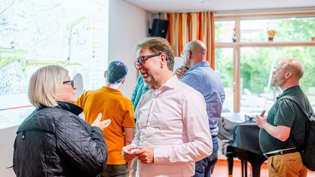 Mobilitätsdezernent Siefert im Gespräch mit der stellv. Ortsbeirätin Puttendörfer Wolfgang Siefert spricht mit der Ortsbeirätin Birgit Puttendörfer in einem Raum mit mehreren Personen, Foto: Michael Braunschädel