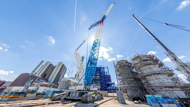 Raupenkran und Kaminschüsse Ein Raupenkran steht auf einer Baustelle