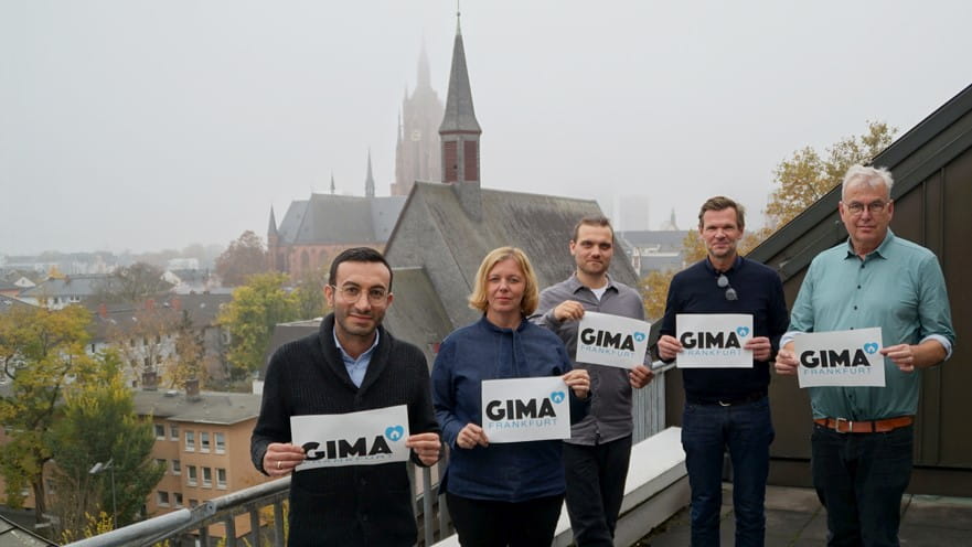 Foto mit Mike Josef, Cora Lehnert, Robin Mohr, Arne Kilian, Matthias Henties, die jeweils ein Schild mit der Aufschrift GIMA Frankfurt hochhalten.