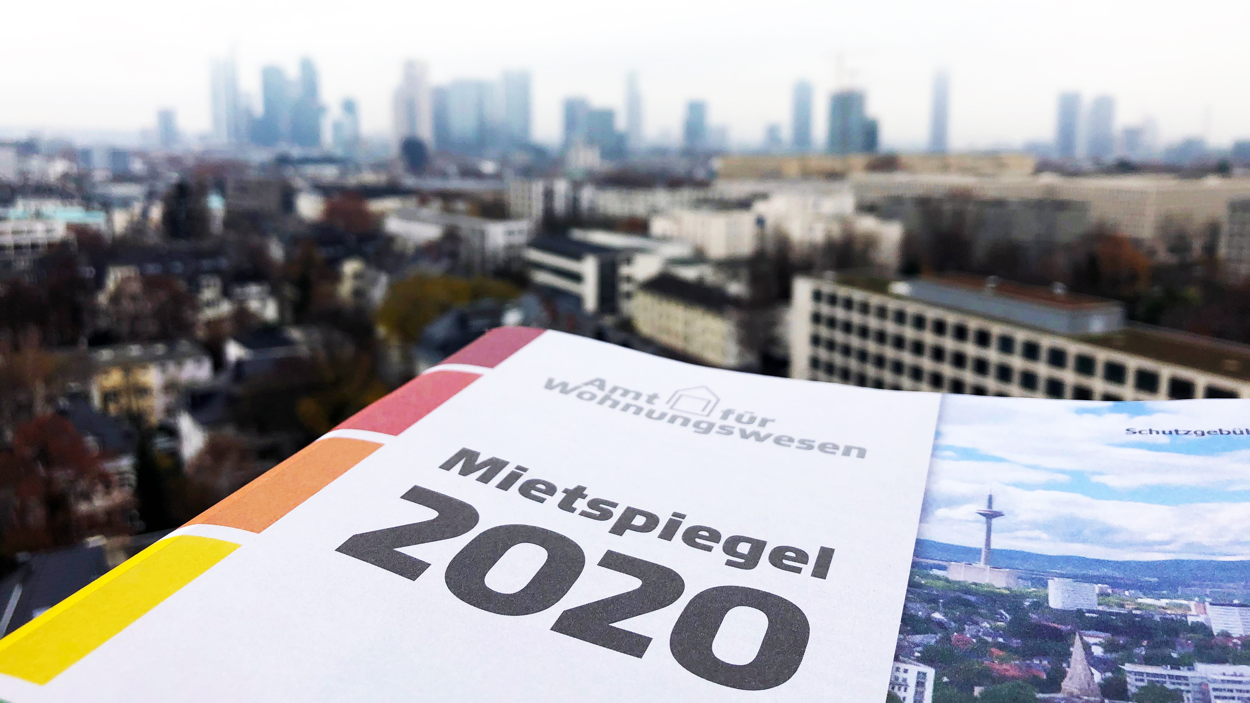 Die Broschüre des Mietspiegels 2020 der Stadt Frankfurt am Main liegt vor der Kulisse Frankfurts.