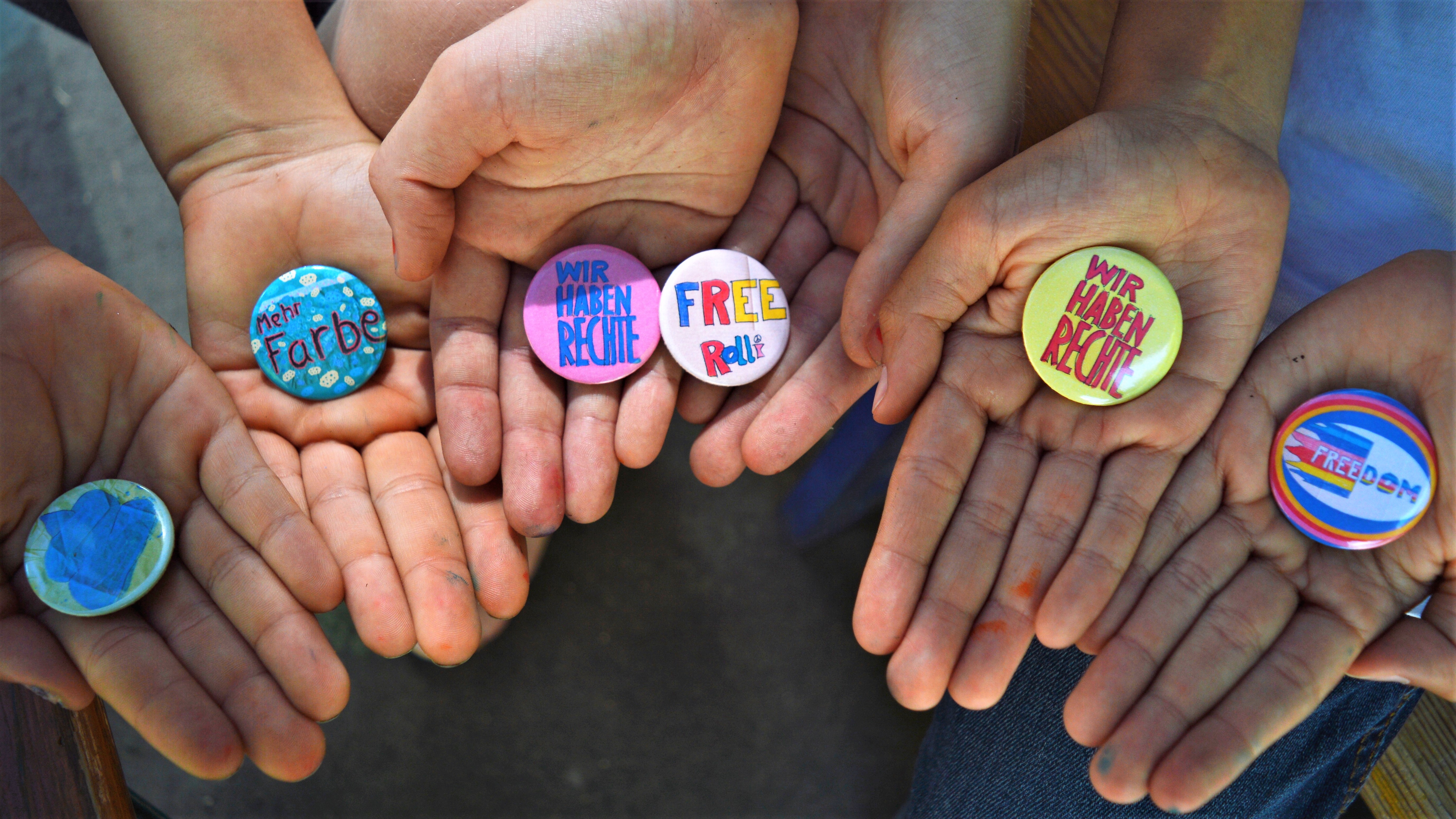 Kinder halten Buttons mit Slogans und Forderungen.