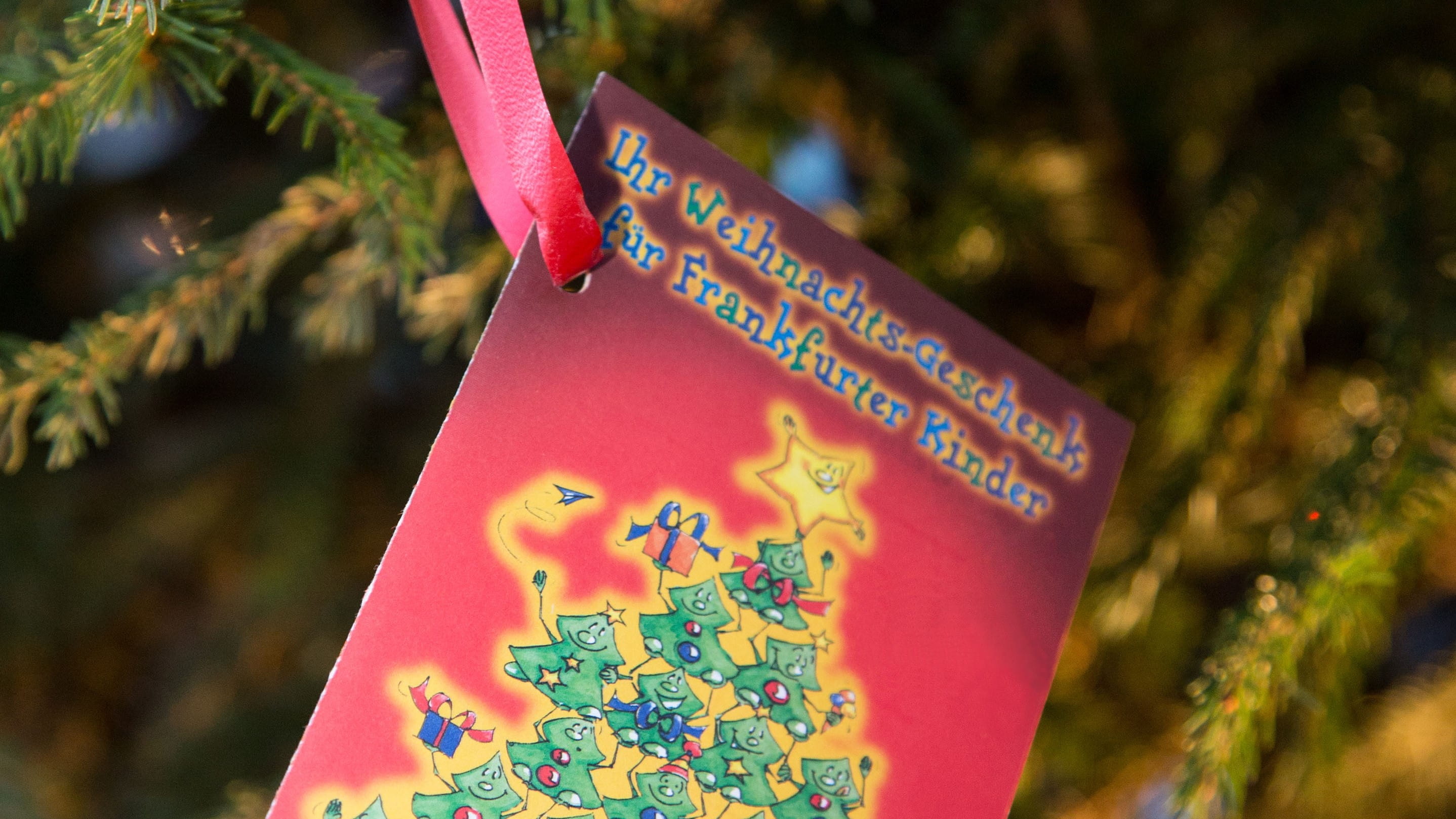 Eine Wunschkarte der Weihnachtsaktion hängt an einem Tannenzweig.