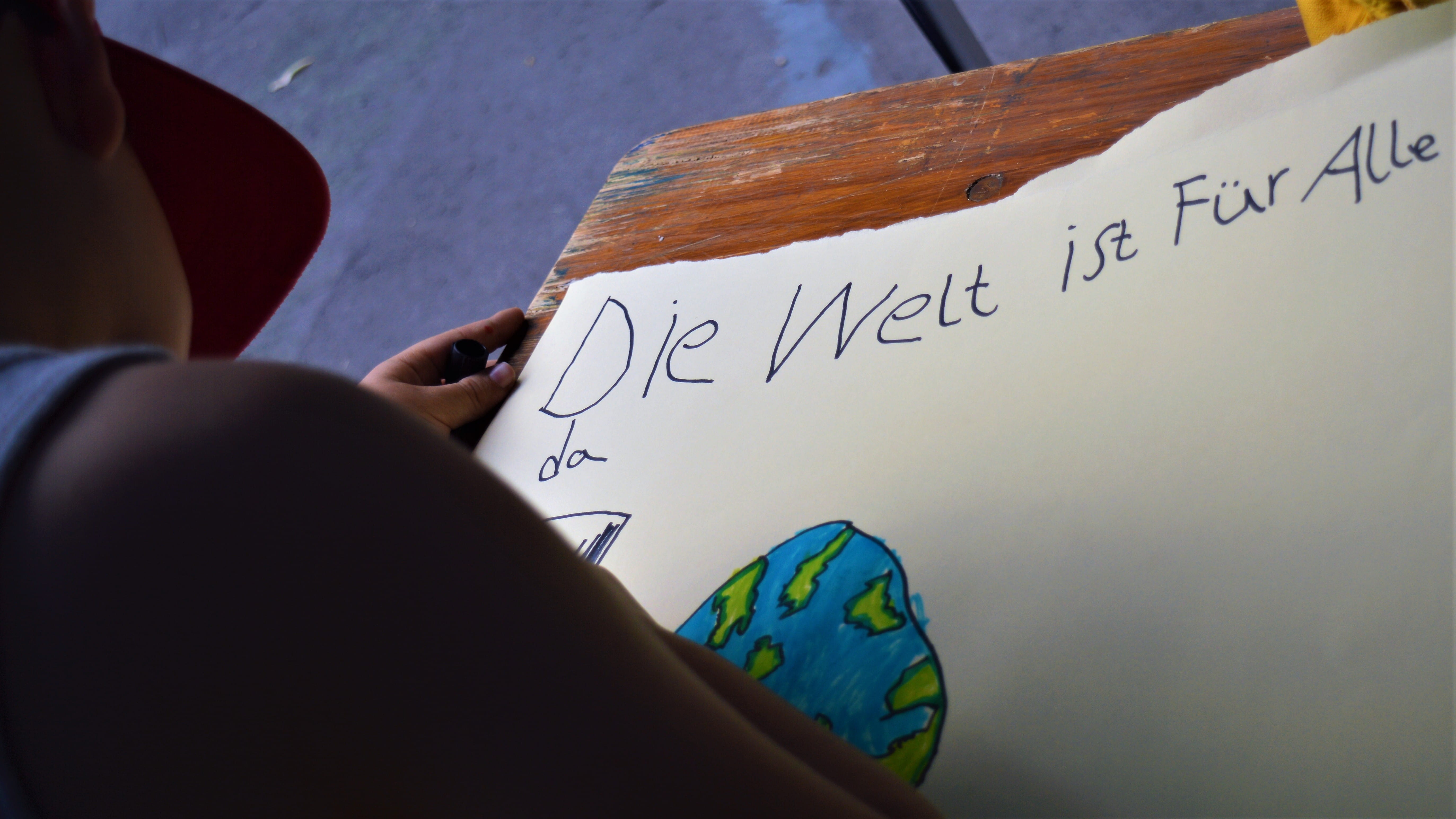 Ein Junge setzt ein Ausrufezeichen hinter den Satz "Die Welt ist für alle da".