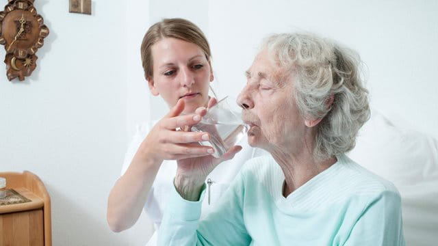 Pflegerin hilft älteren Dame