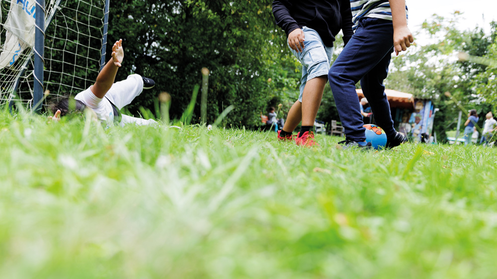 Besucher des Kinderhaus Höchst beim Fußballspielen auf einer grünen Wiese