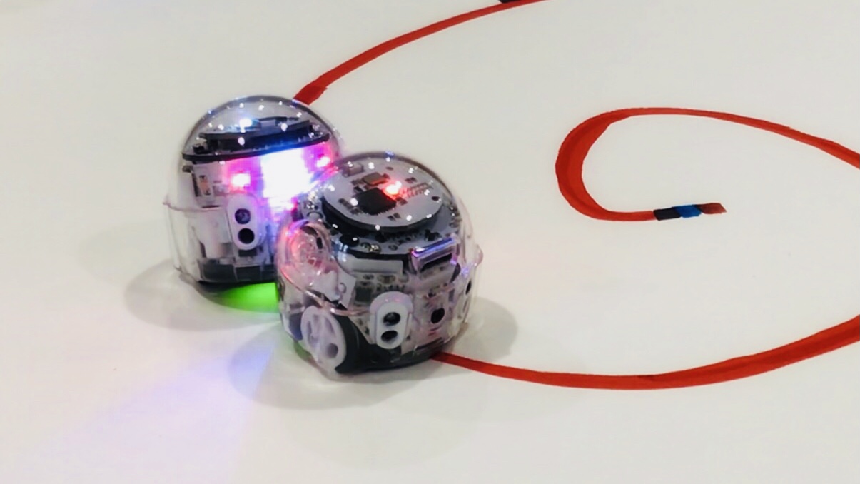Zwei Ozobot Roboter fahren auf roter Linie