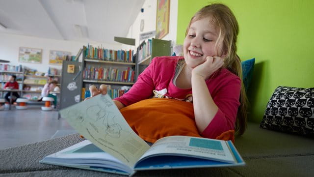 Lesendes Mädchen in der Schulbibliothek der Friedrich-Fröbel-Schule