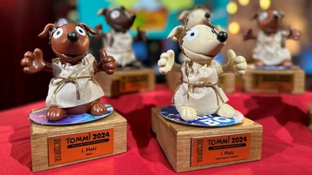 TOMMi Trophäen 2024 TOMMi Trophäen 2024. Die Trophäen sind Hunde in einer Art Tunika und Kranz auf dem Kopf.