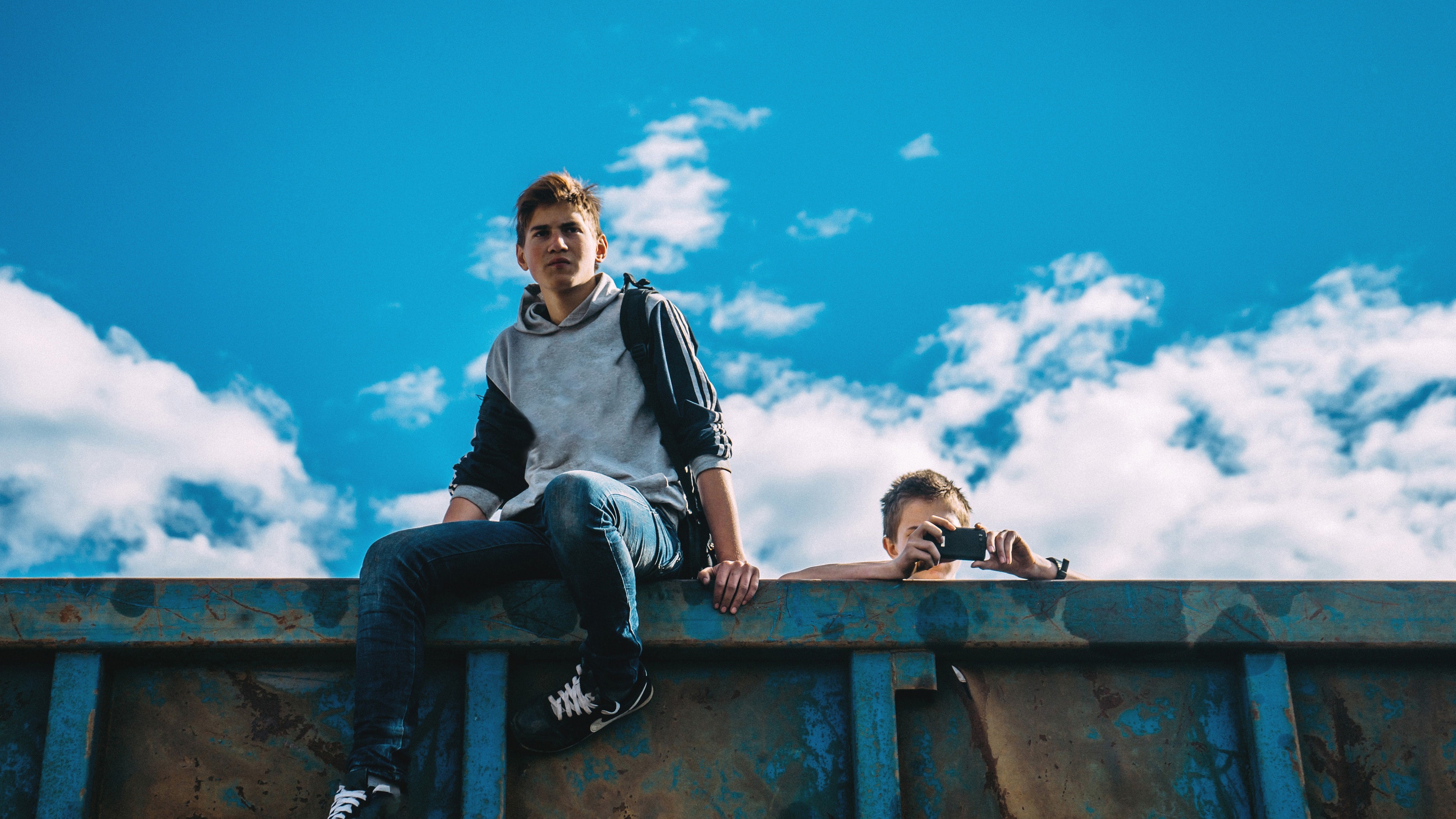 Zwei junge Männer sitzen auf einer Mauer. 