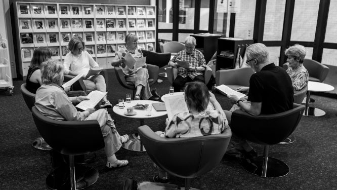 Eine Gruppe von Personen sitzt in einem Kreis und liest sich vor. 