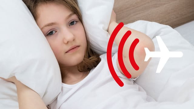 Ein Mädchen liegt im Bett und hält sich ein Kissen an die Ohren.