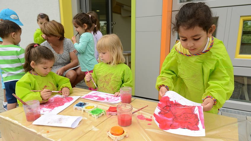 Kinder malen mit bunten Farben ein Bild.