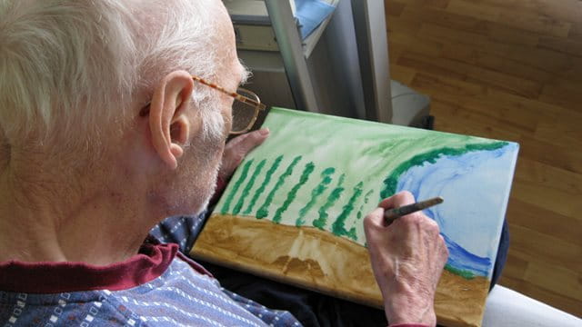 Ein älterer Herr malt ein Bild.