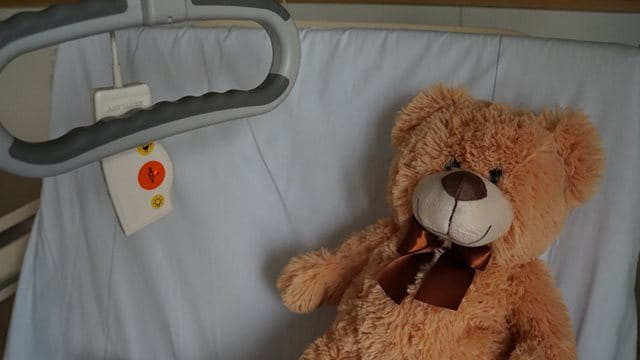 Ein Teddy liegt in einem Krankenhausbett