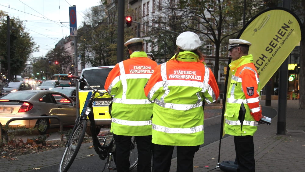 Mitarbeiter der Städtischen Verkehrspolizei kontrollieren Verkehrsteilnehmende im Rahmen der Aktion "Lass Dich sehen"
